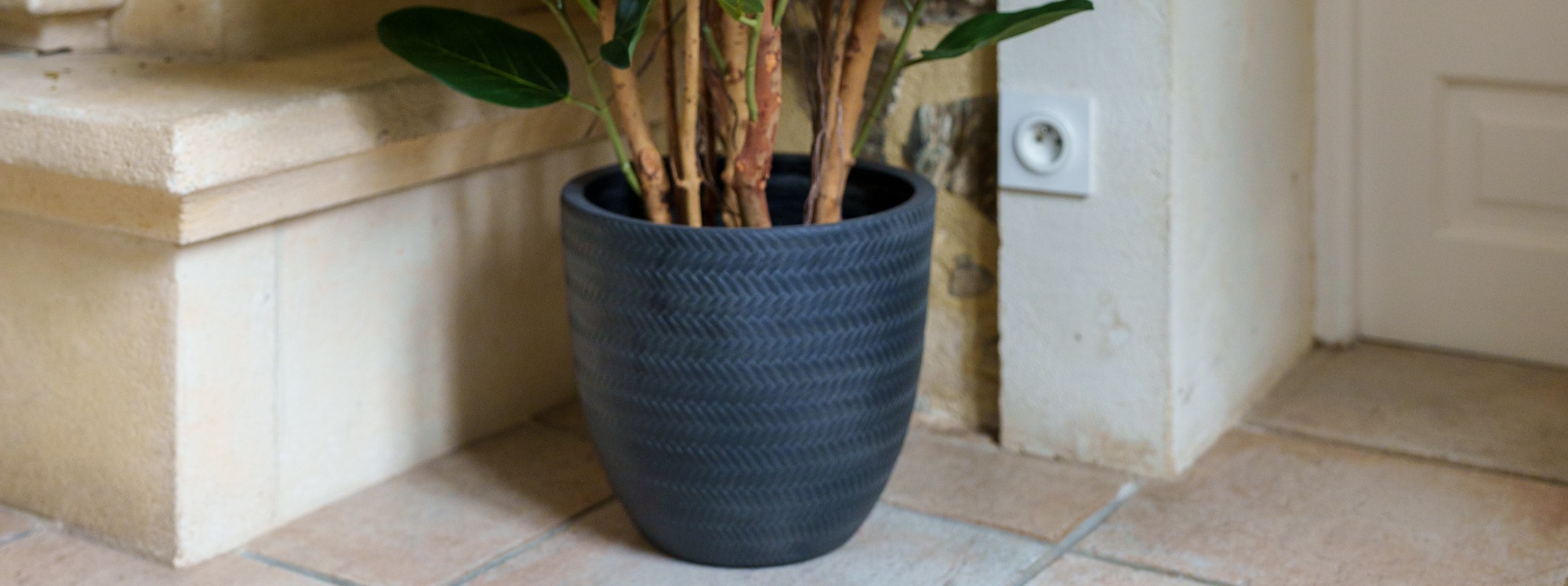 Pot noir à motif tressé près d'un mur